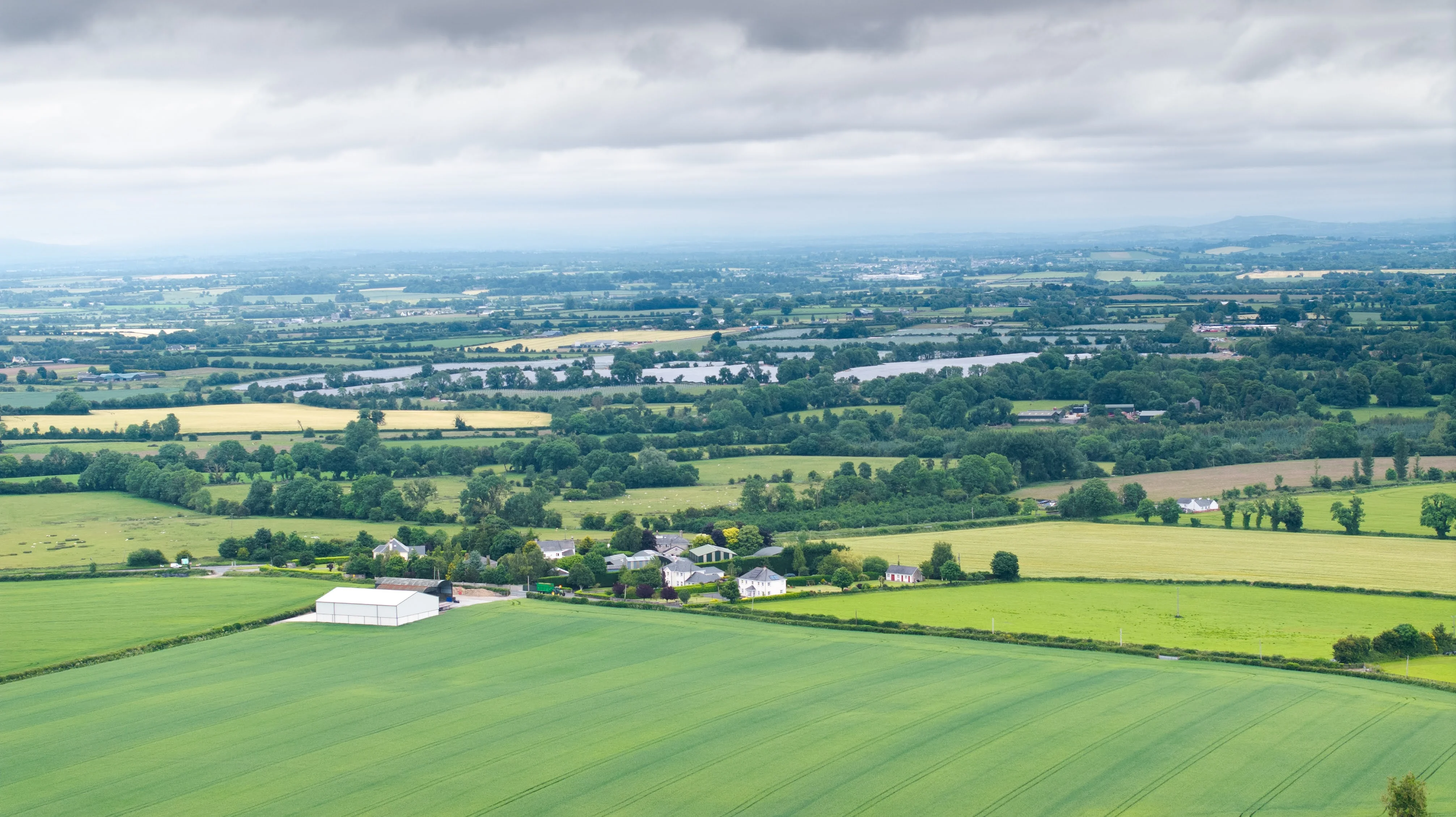 Aerial view of green farmland with scattered houses and countryside